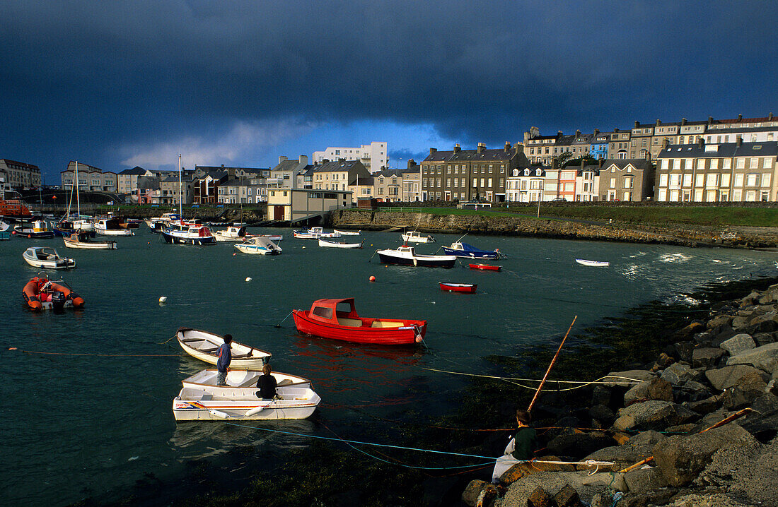 Boys on boats at the harbour under dark clouds, Portrush, County Antrim, Ireland, Europe