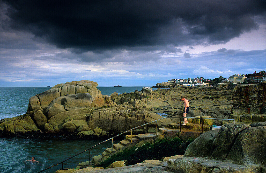 People bathing in the sea under dark clouds, Sandy Cove, County Dublin, Ireland, Europe