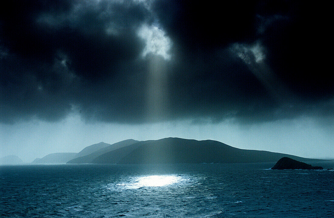 Sonnenstrahlen scheinen durch dunkle Wolkendecke in der Dingle Bay, Great Blasket Island, County Kerry, Irland, Europa