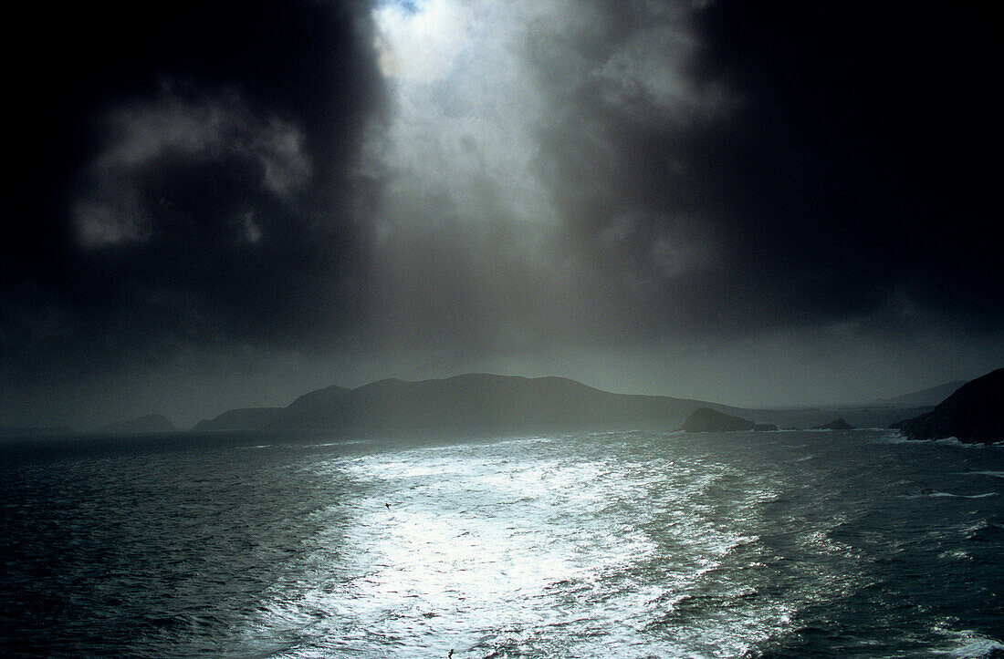 Sonnenstrahlen scheinen durch dunkle Wolkendecke in der Dingle Bay, Great Blasket Island, County Kerry, Irland, Europa