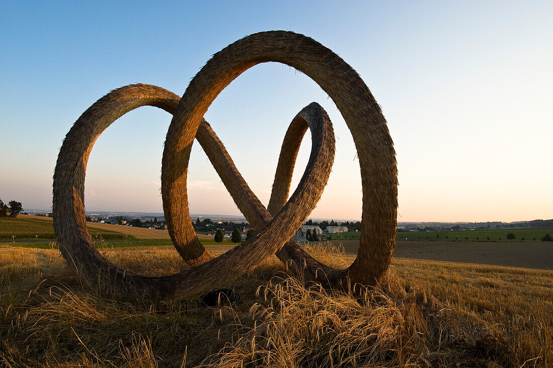Skulptur aus Stroh auf einem Feld in der Abenddämmerung, Linz, Oberösterreich, Österreich