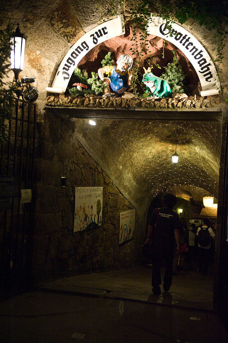 Menschen gehen am Abend durch den Eingang zur Grottenbahn, Linz, Oberösterreich, Österreich