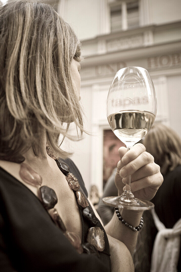 Blond woman holding a wine glass turning away, Linz, Upper Austria, Austria