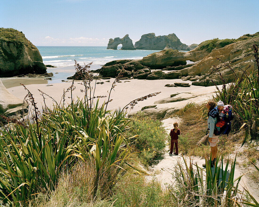 Frau und Kinder wandern zum Strand, Wharariki Beach, Nordwestküste, Südinsel, Neuseeland
