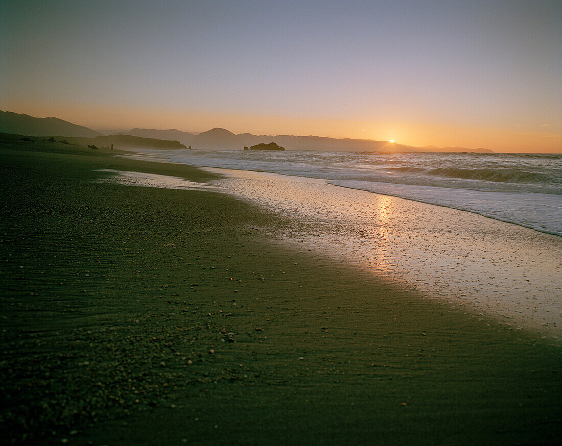 Menschenleerer Strand mit Kieseln bei Sonnenuntergang, Okuru Beach, Westküste, Südinsel, Neuseeland