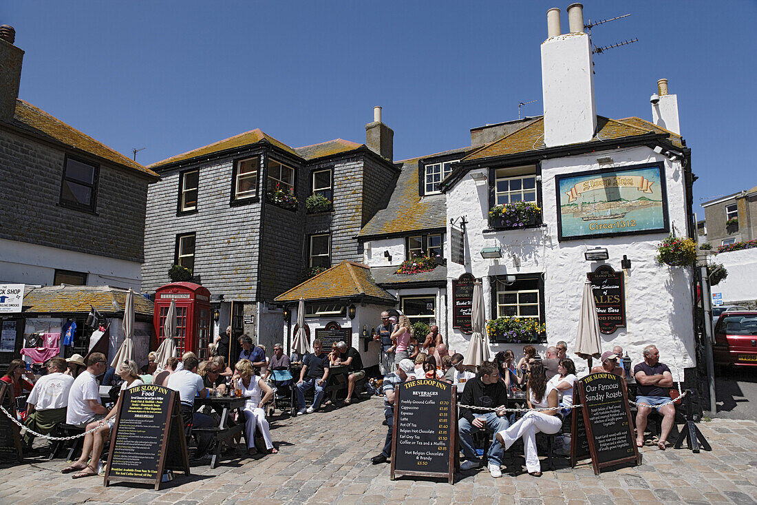 People sitting in front of the Sloop Inn, St. Ives, Cornwall, England, United Kingdom