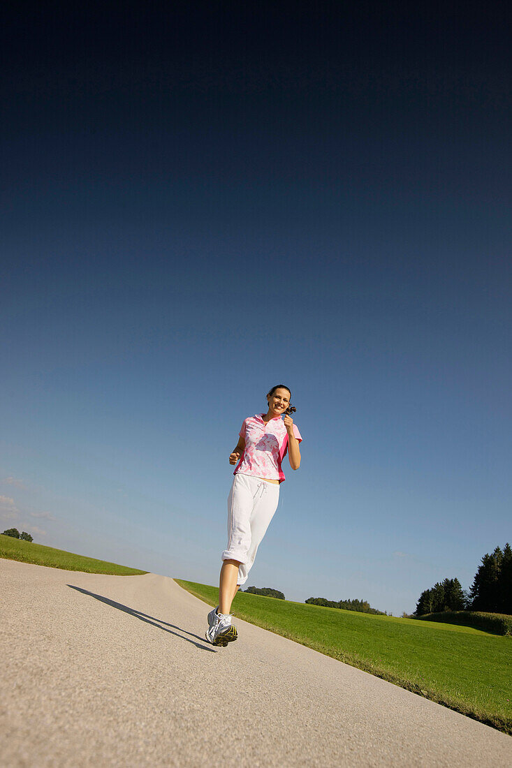 Woman walking along road, Munsing, Bavaria, Germany