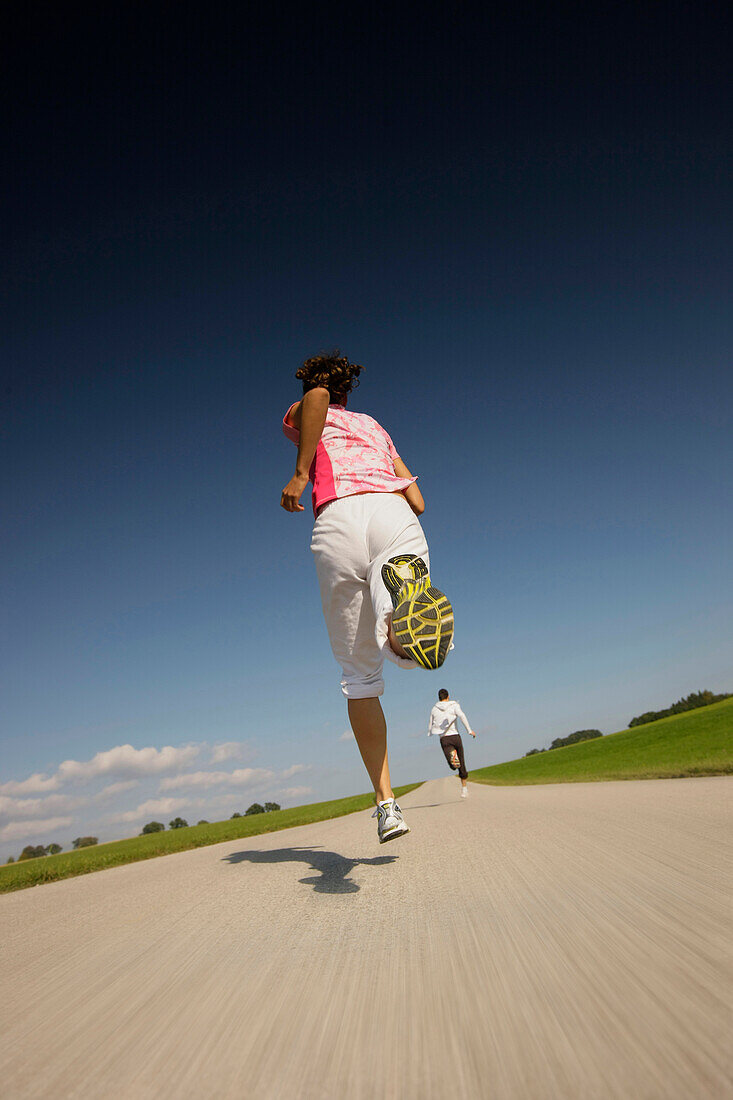 Couple jogging along road, Munsing, Bavaria, Germany