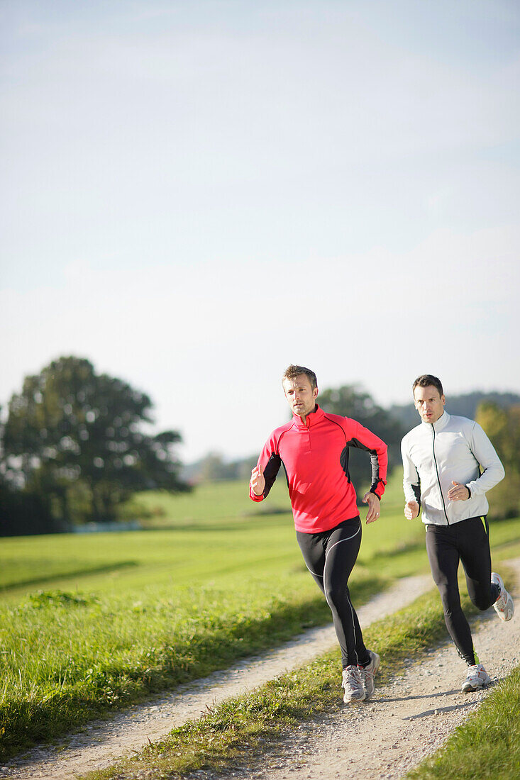 Zwei Männer joggen über Feldweg, Münsing, Bavaria, Germany
