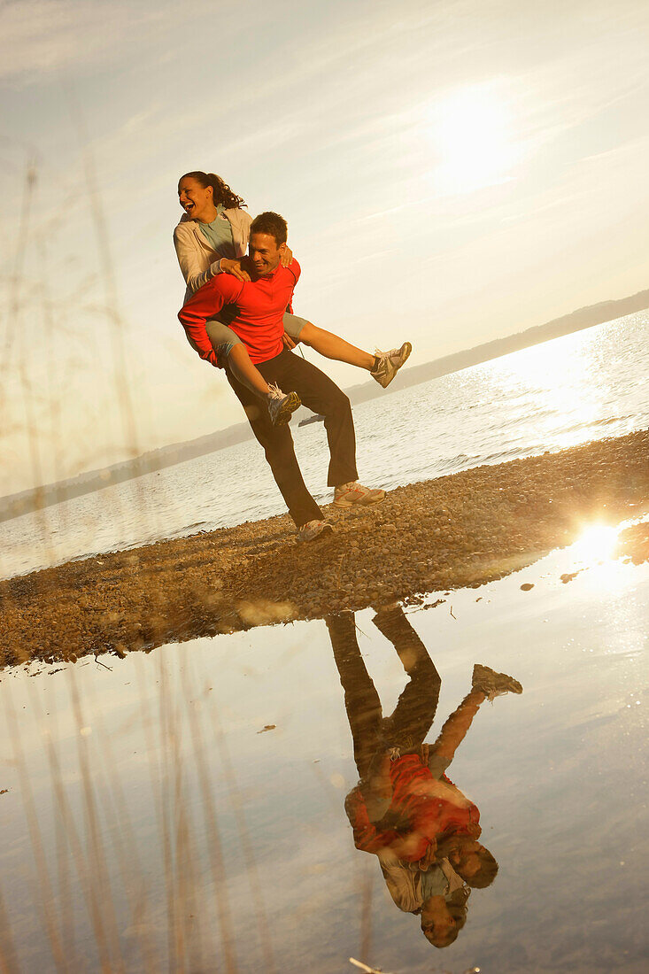 Man giving woman piggyback, Ambach, Bavaria, Germany