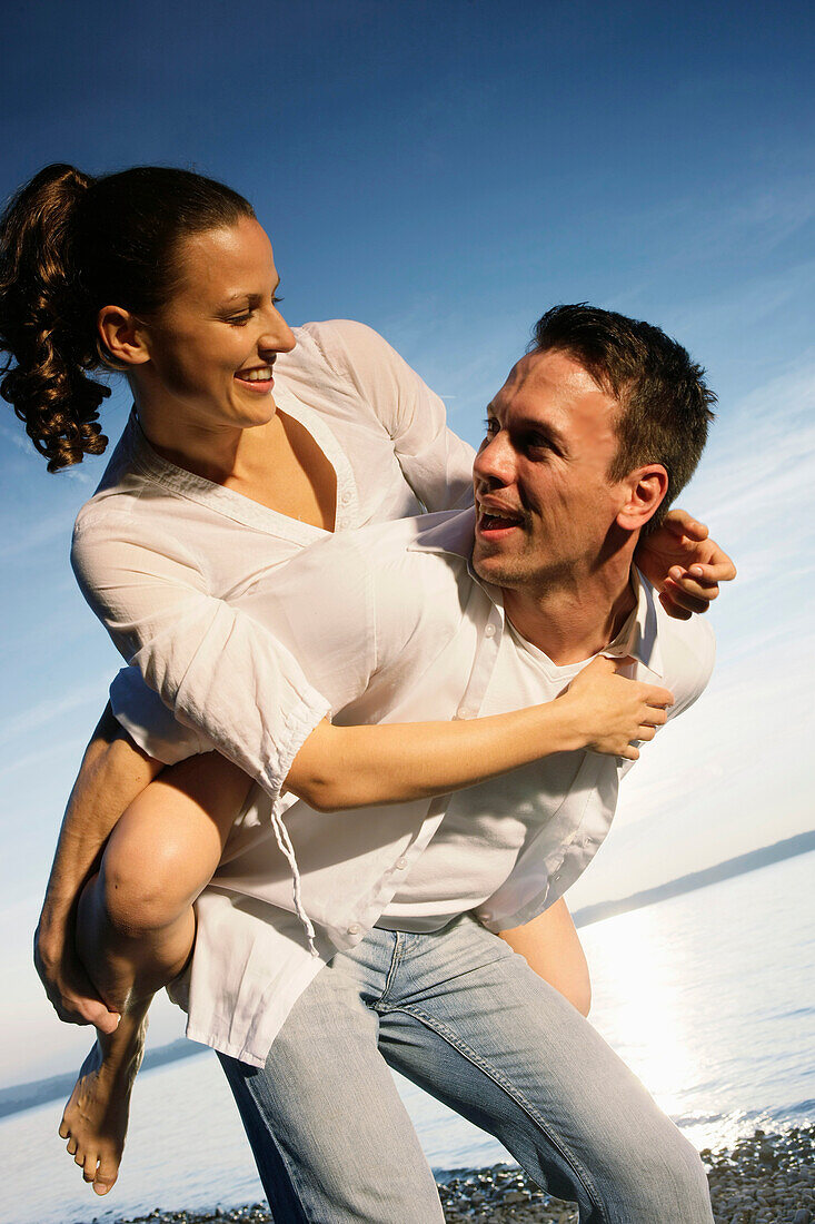 Man giving woman piggyback, Ambach, Bavaria, Germany