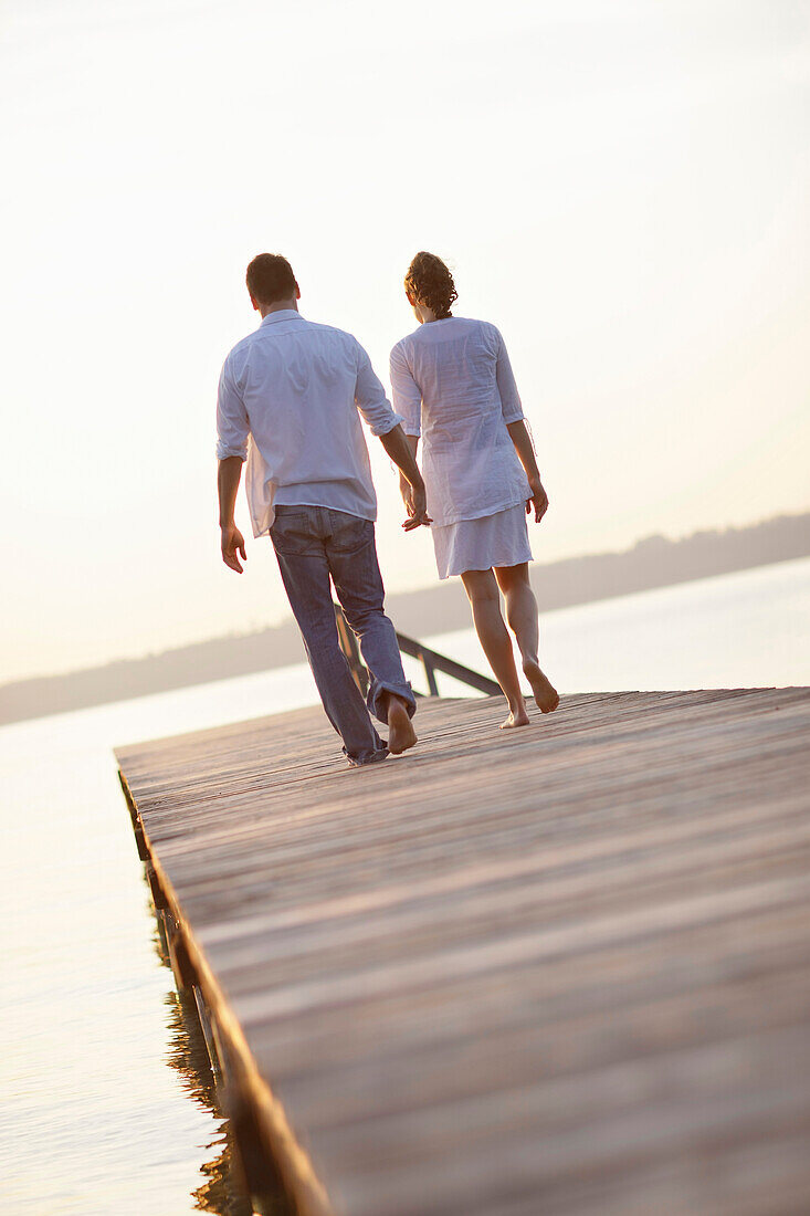 Paar läuft Hand in Hand über einen Steg, Ambach, Starnberger See, Bayern, Deutschland