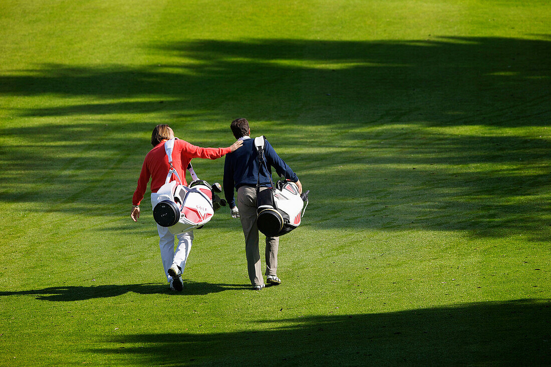 Two golfers walking over golf course, Strasslach-Dingharting, Bavaria, Germany