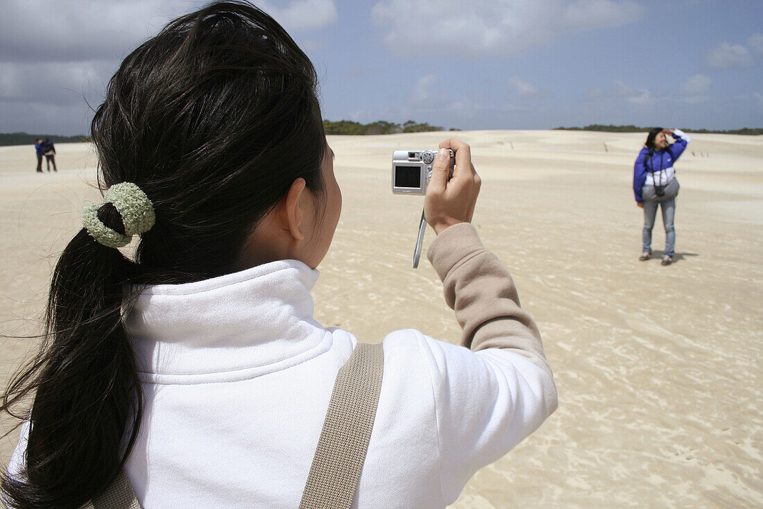 Girl taking picture with digital camera, Henty Dunes, West Coast, Tasmania, Australia