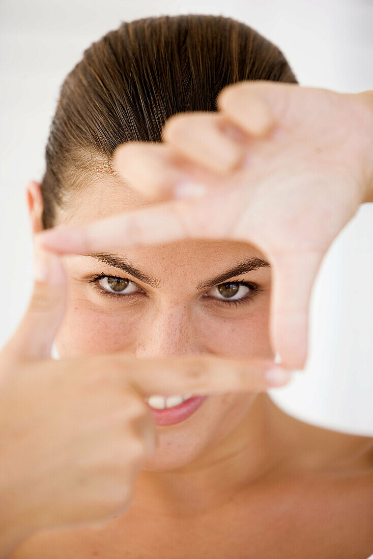 Brünette Frau mit Handzeichen vor dem Gesicht