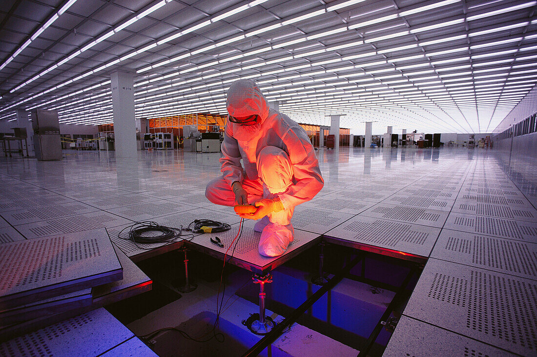 Worker checking floor wiring in semiconductor plant. USA