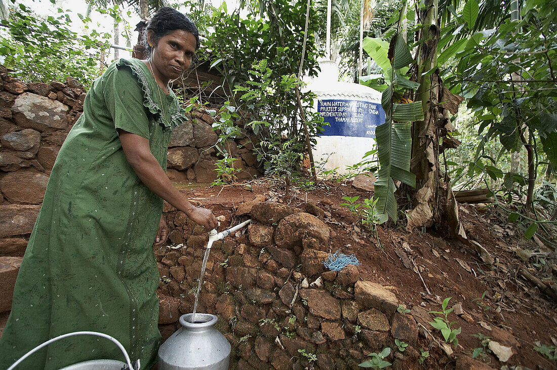 Woman collecting safe drinking water. Kerala, India