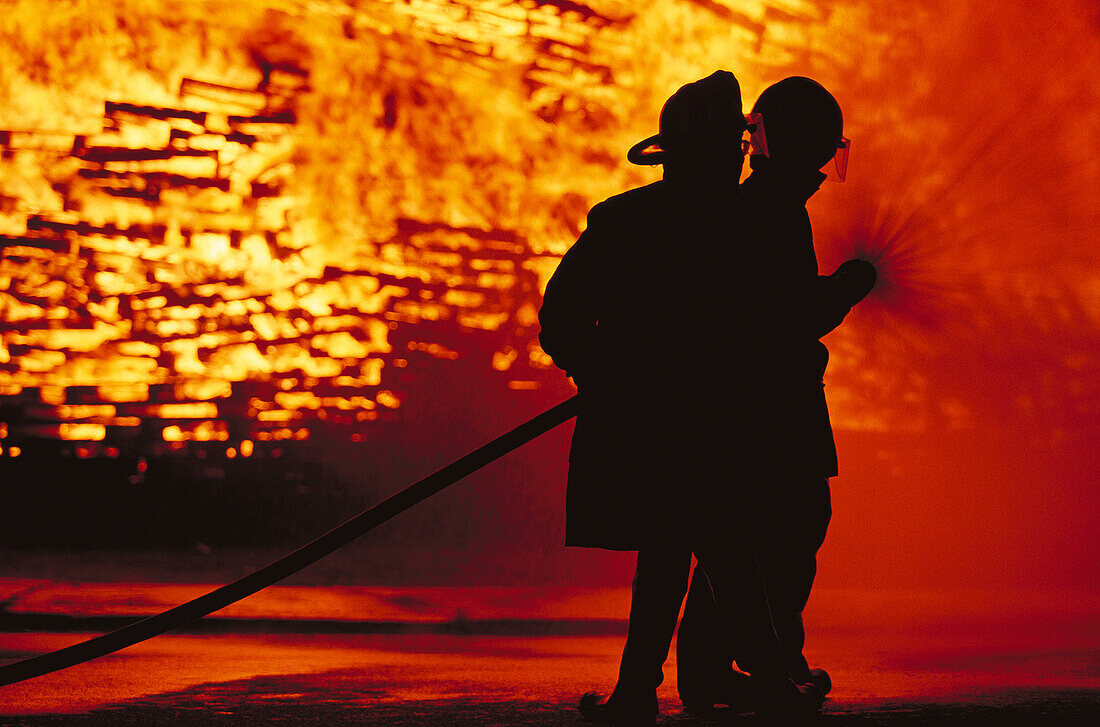 Silhouette of firemen in front of fire