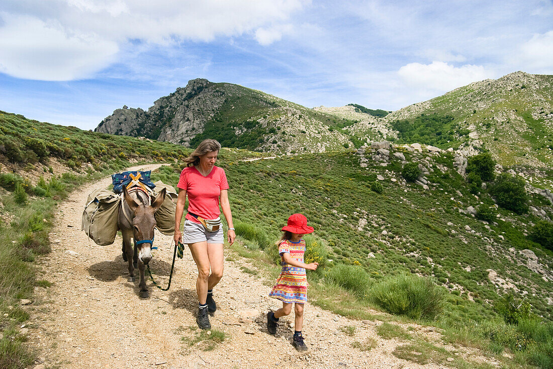 Mutter und Tochter wandern mit einem Esel an der Leine in den Cevennen, Frankreich