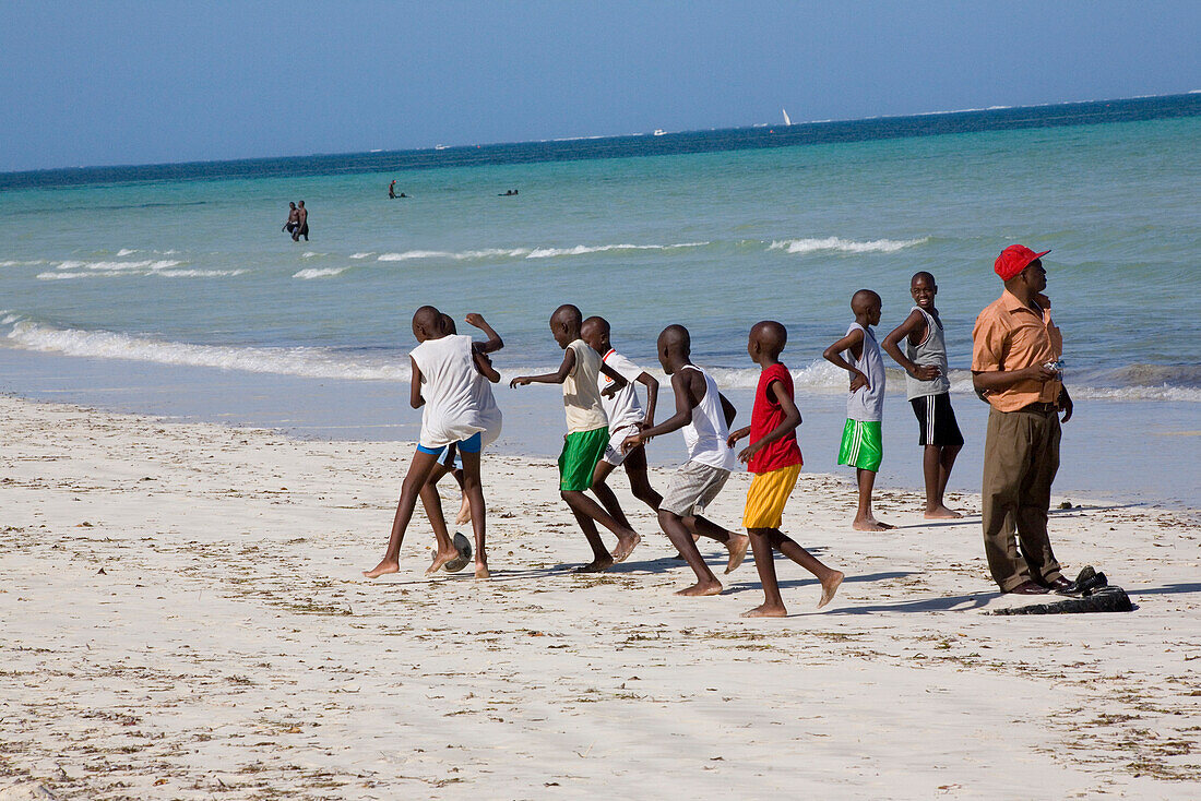 Kenyan boys playing football at the Public Beach of Mombasa, Kenya, Africa