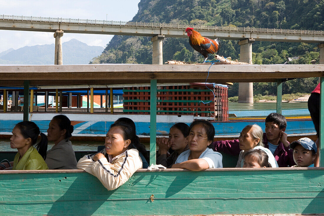 Menschen und ein Hahn in einem Boot auf dem Fluss Nam Ou, Provinz Luang Prabang, Laos