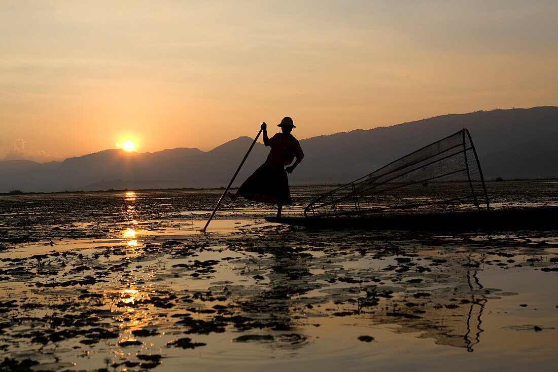 Intha fisherman on his fishing boat on Inle Lake at sunset, Shan State, Myanmar, Burma