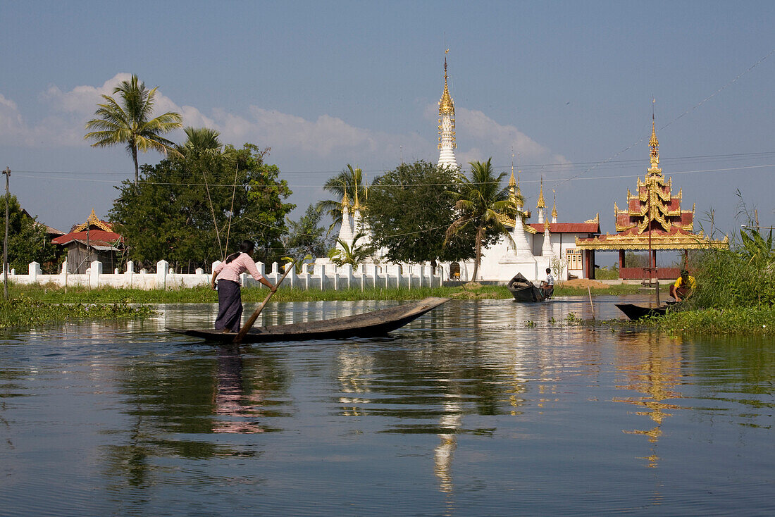 Young woman in a canoe in front of pagodes at Inle Lake, Myanmar, Shan State, Burma