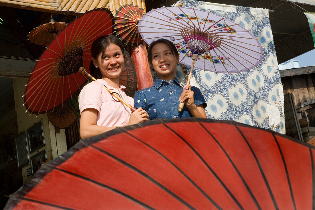 Zwei junge burmesische Frauen mit bunten Papierschirmen aus Bambus in Mandalay, Myanmar, Burma