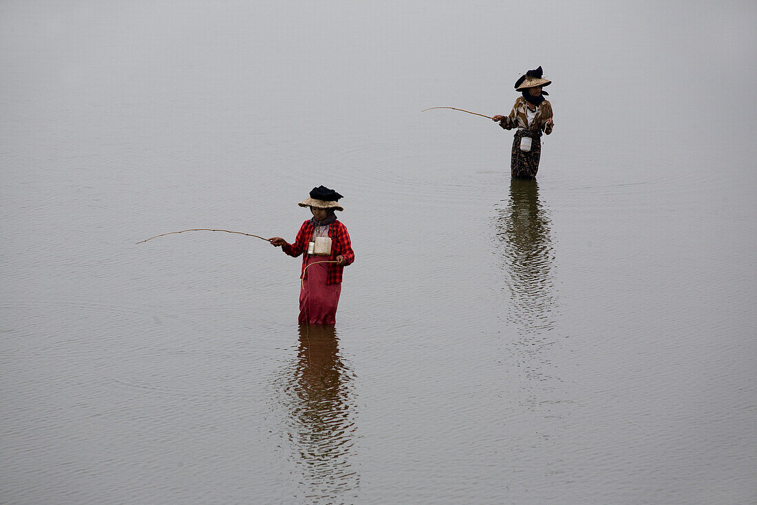 Frauen fischen stehend mit Angel im Taungthaman See in Amarapura bei Mandalay, Myanmar, Burma