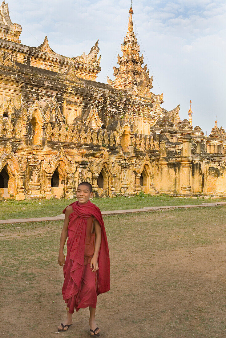 Young burmese monk in front of a temple on Inwa island ( Ava ) at Ayeyarwady River near Amarapura, Myanmar, Burma