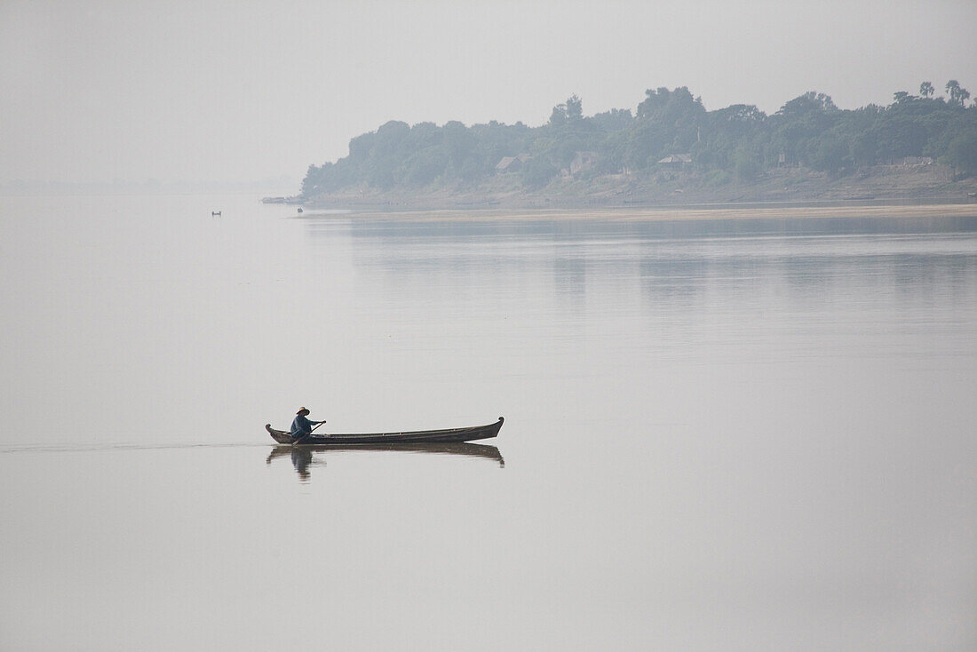Man in a canoe on Ayeyarwady river between Mandalay and Bagan in Myanmar, Burma
