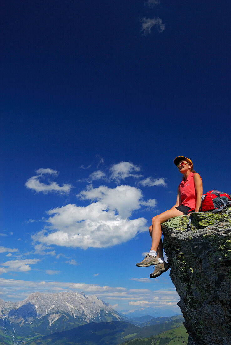 Junge Frau auf Felsen sitzend mit Hochkönig in den Berchtesgadener Alpen im Hintergrund, Hundstein, Salzburger Schieferalpen, Salzburg, Österreich