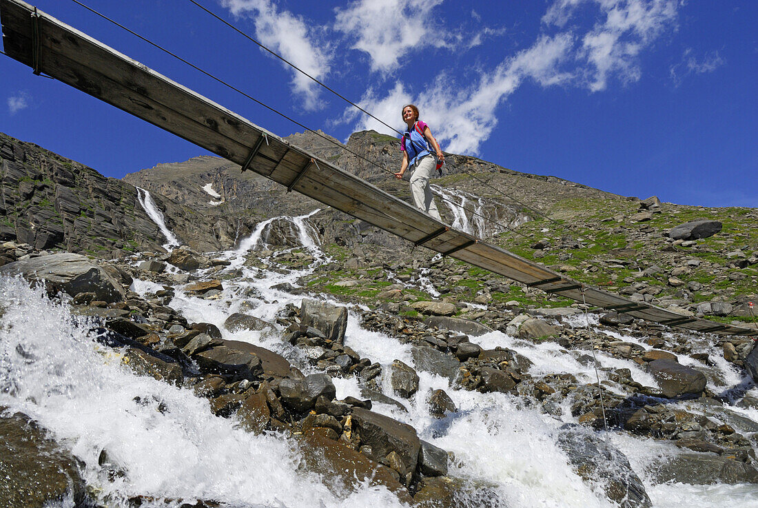 Woman on a bridge crossing stream, National Park Hohe Tauern, Salzburg, Austria