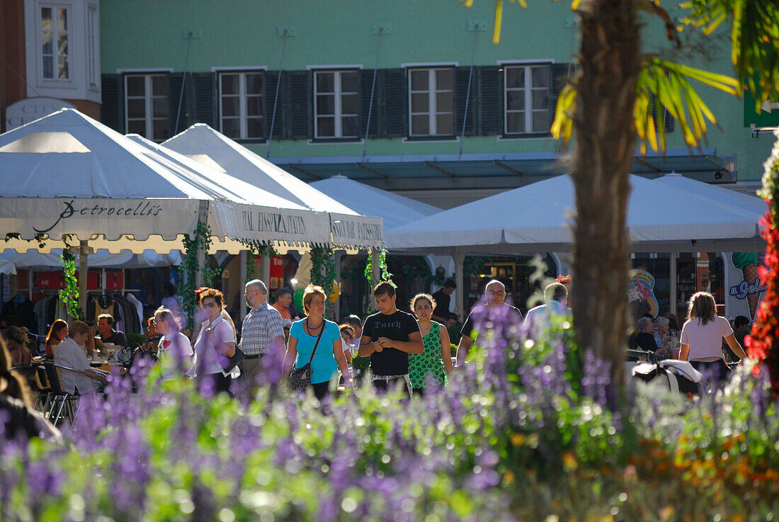 Personen am Hauptplatz in Lienz, Blumenschmuck unscharf im Vordergrund, Fußgängerzone, Osttirol, Österreich