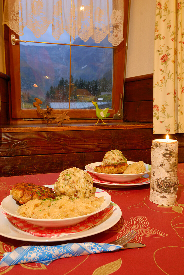 gedeckter Tisch mit zwei Portionen Tiroler Kaspressknödel und Speckknödel mit Sauerkraut, Tirol, Österreich