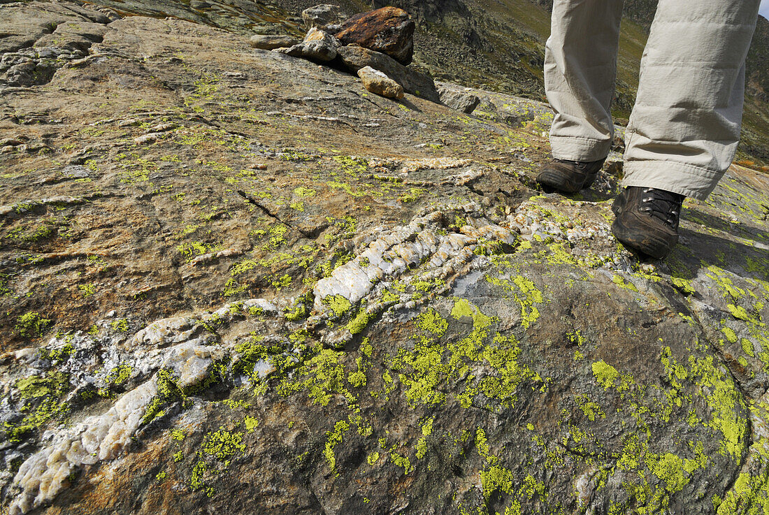 Person steht auf einer Felsplatte mit Quarzader, Stubaier Alpen, Stubai, Tirol, Österreich