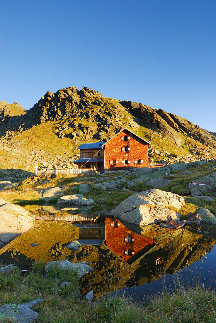 Bremer Huette and reflections in little lake, Stubaier Alpen range, Stubai, Tyrol, Austria
