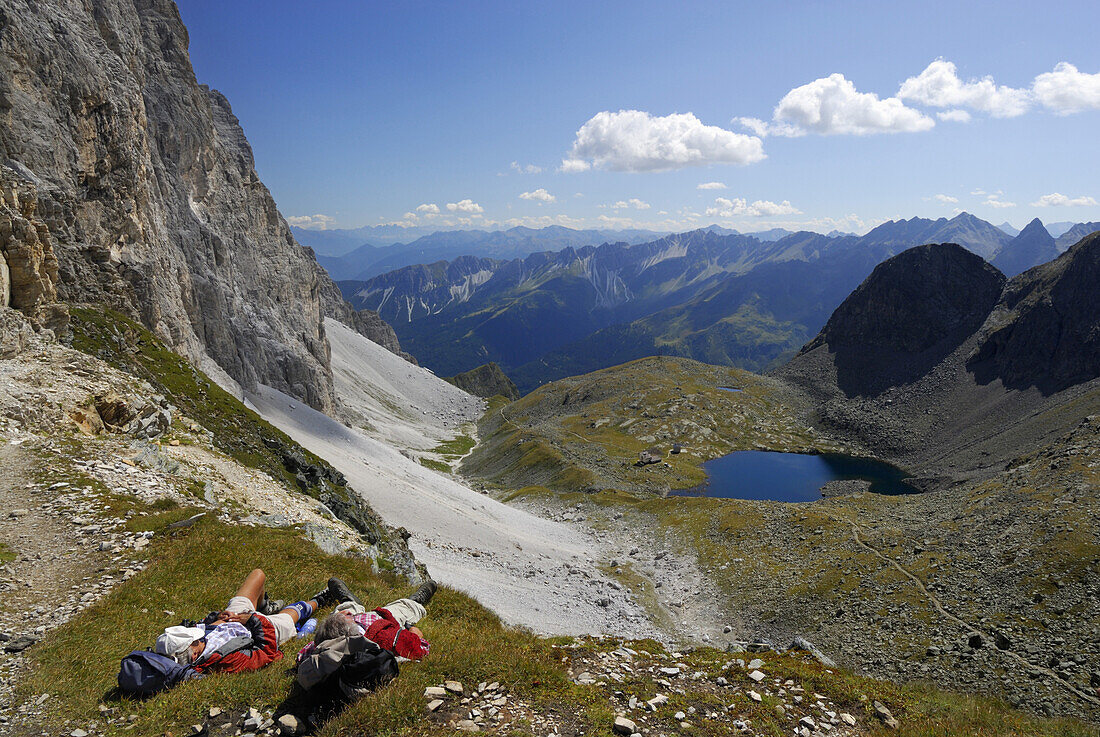 Two hikers lying on grass, Stubai Alps, Stubai, South Tyrol, Italy