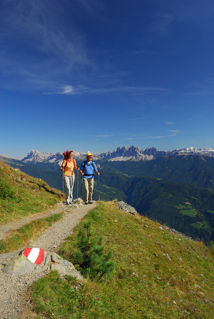 couple on trail with view to Dolomites with Peitlerkofel, Geislergruppe and Sella range, hut Radlseehuette, Sarntaler Alpen, Sarntal range, South Tyrol, Italy