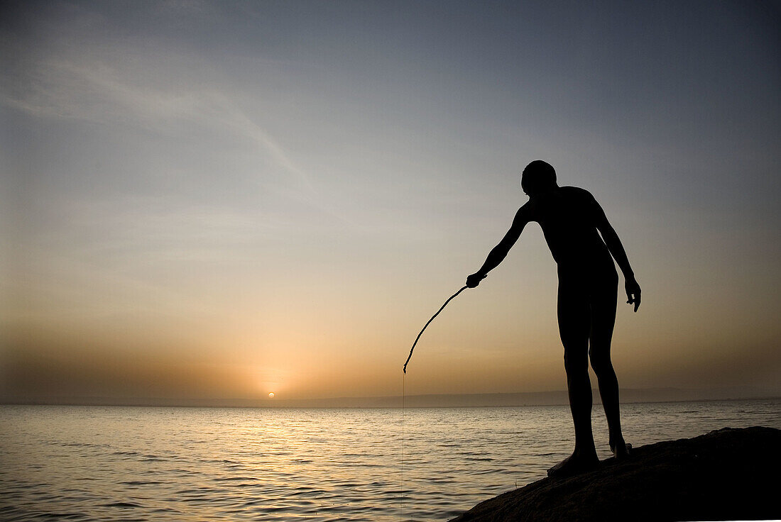 Young African man fishing at sunset. South Ethiopia. African people