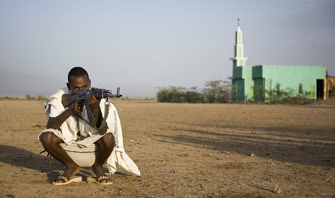 Afar man holding gun and mosque in background. Ethiopia. African tribes