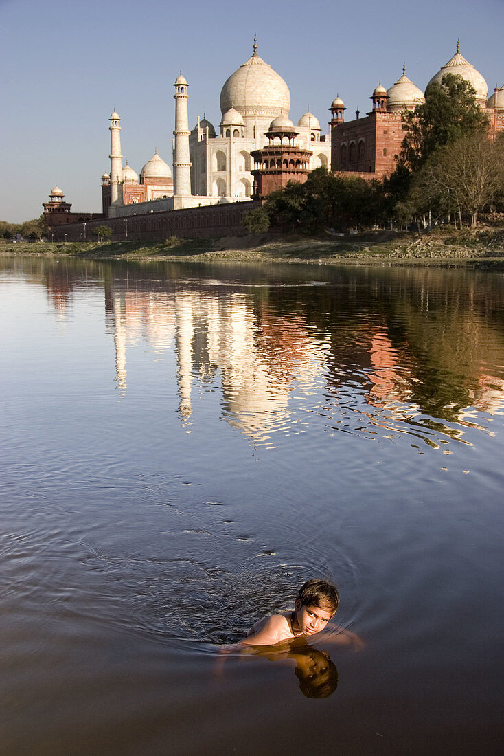 Boy swimming in Yamuna River and Taj Mahal in background, Agra. Uttar Pradesh, India