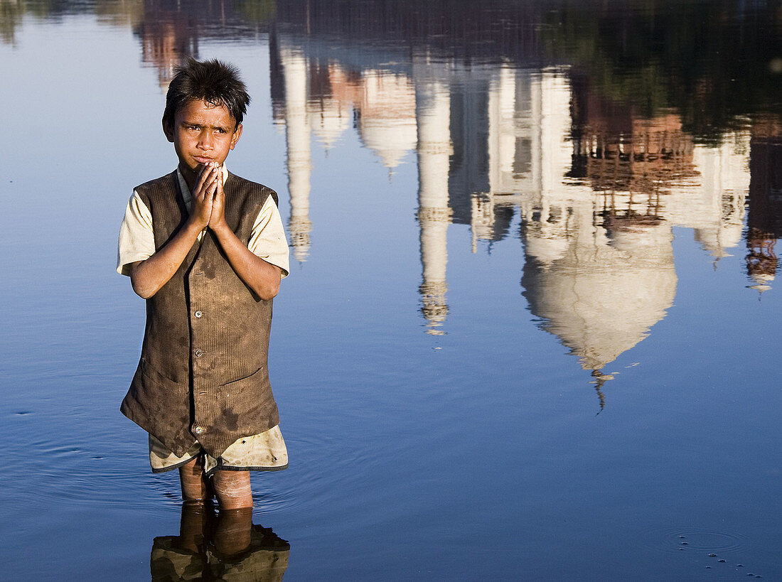 Boy praying in Yamuna River and Taj Mahal reflection, Agra. Uttar Pradesh, India