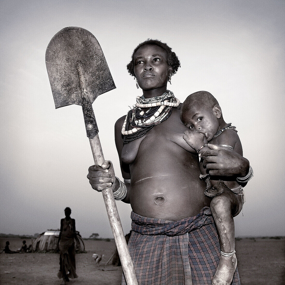 Dasanech woman and child holding shovel. South Ethiopia, African tribes