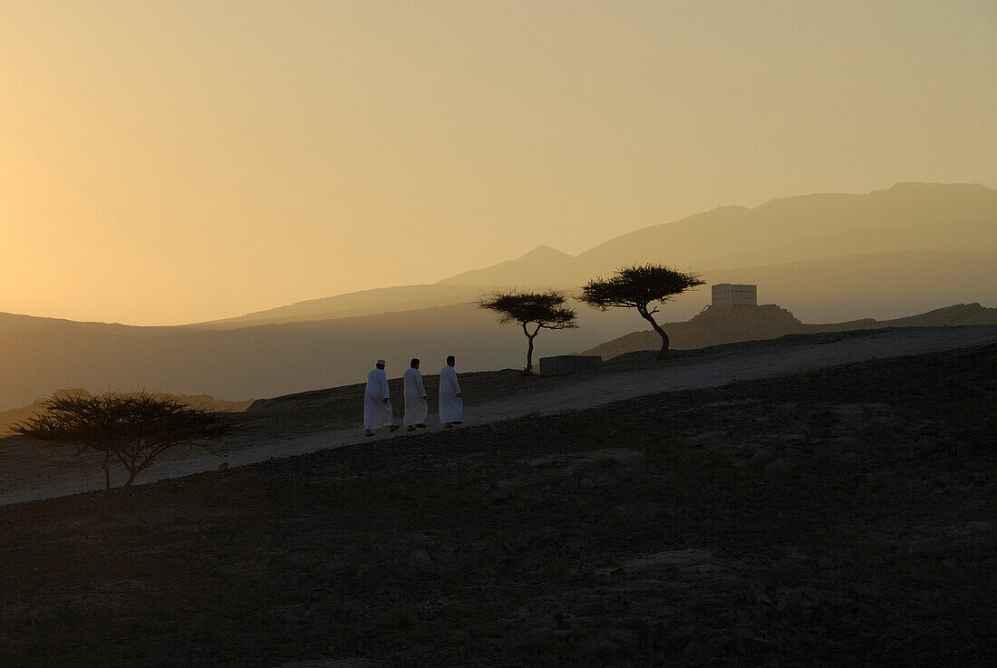 Local men on a path at dawn, Al Hajar mountains, Musandam, Oman, Asia