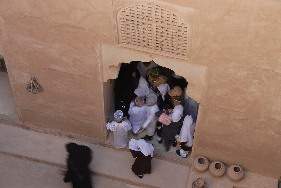 Einheimische drängen sich unter einem Tor von Fort Jabrin, Oman, Asien