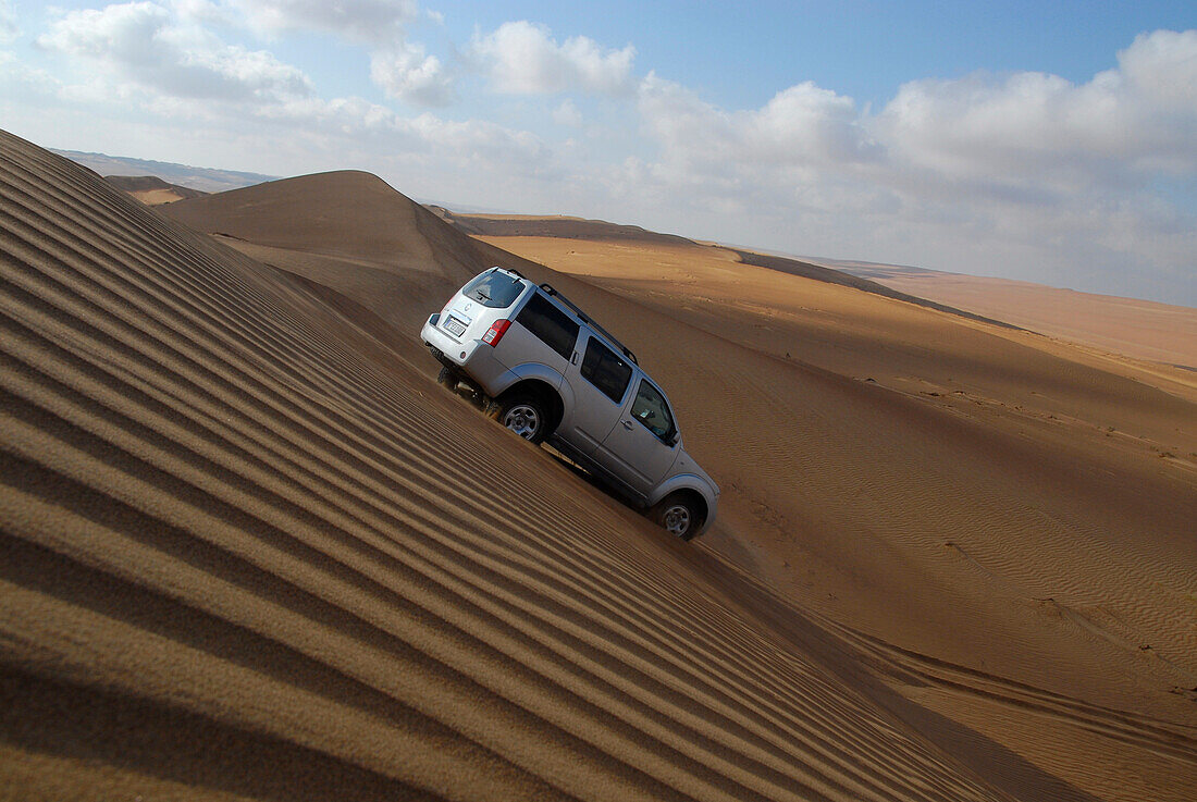 Ein Geländewagen fährt eine Sanddüne hinunter, Wahiba Sands, Oman, Asien