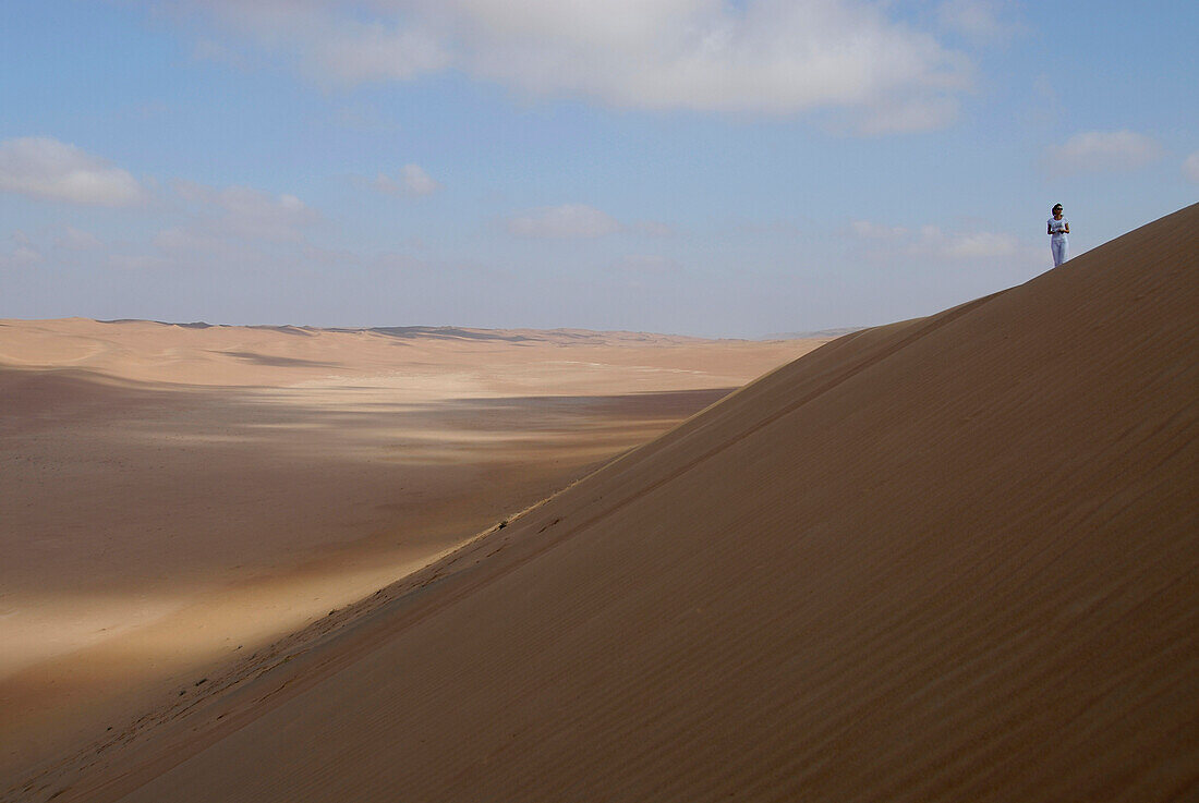 A person standing on a sand dune, Wahiba Sands, Oman, Asia
