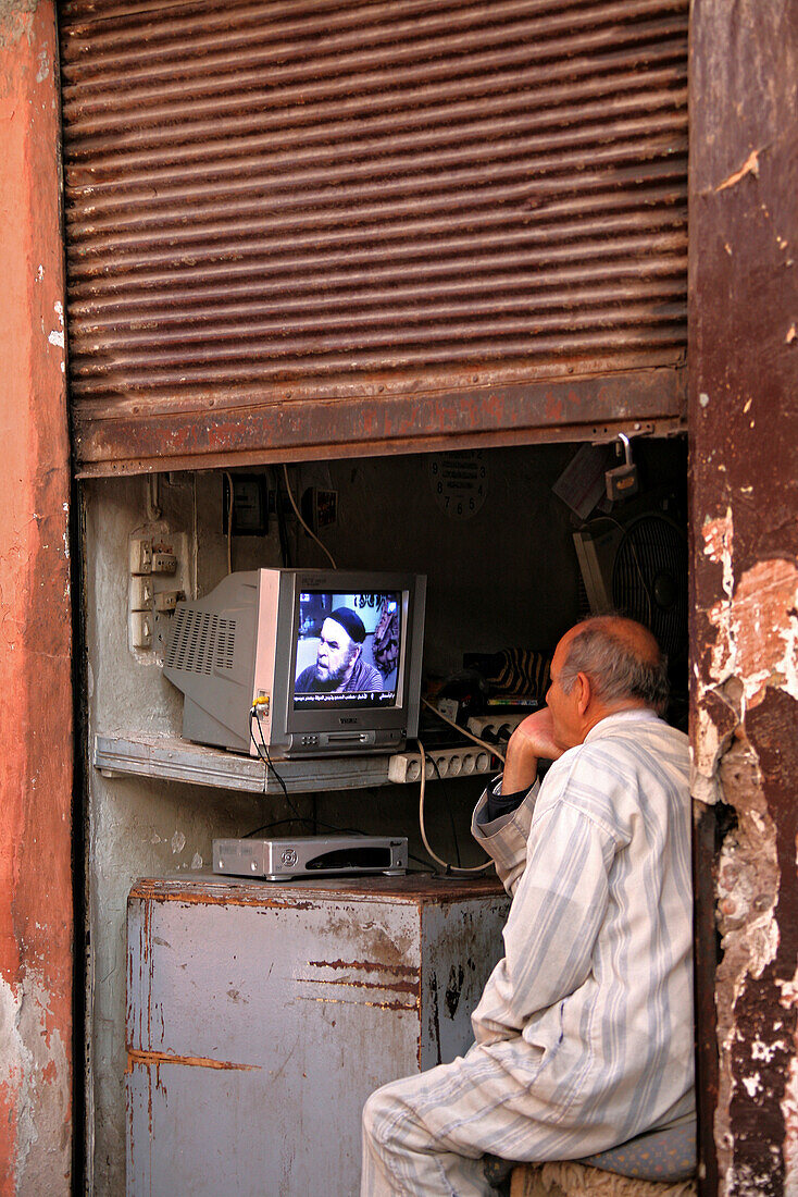 Shopkeeper at the souk of Marrakesh watching television, Marrakesh, Morocco, Africa