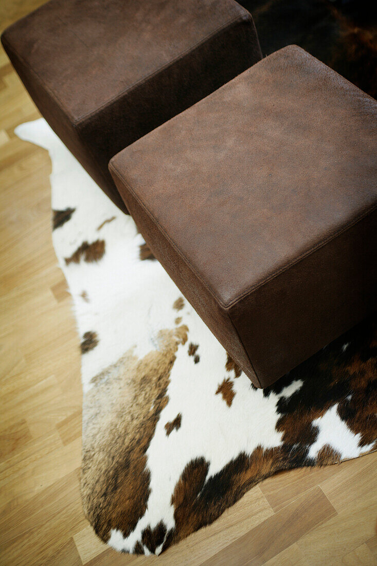 Hocker und Kuhfell auf einem Parkettboden